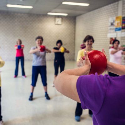 mehrere Senioren haben einen Ball in ihren Händen die Arme in der Wagrechten